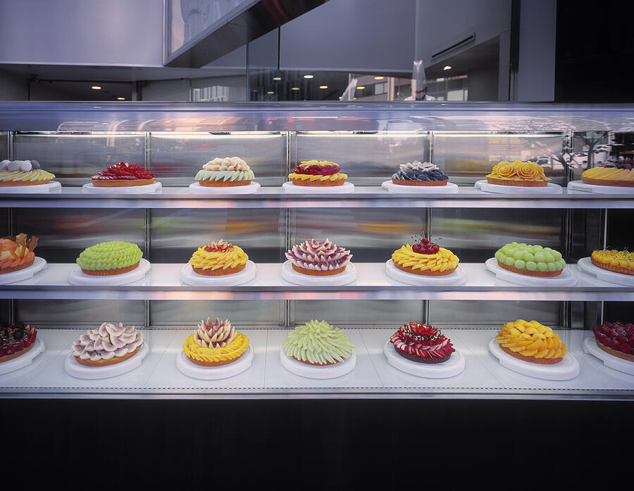 Display with collection of colorful fruit tarts. Photograph by EschCollection