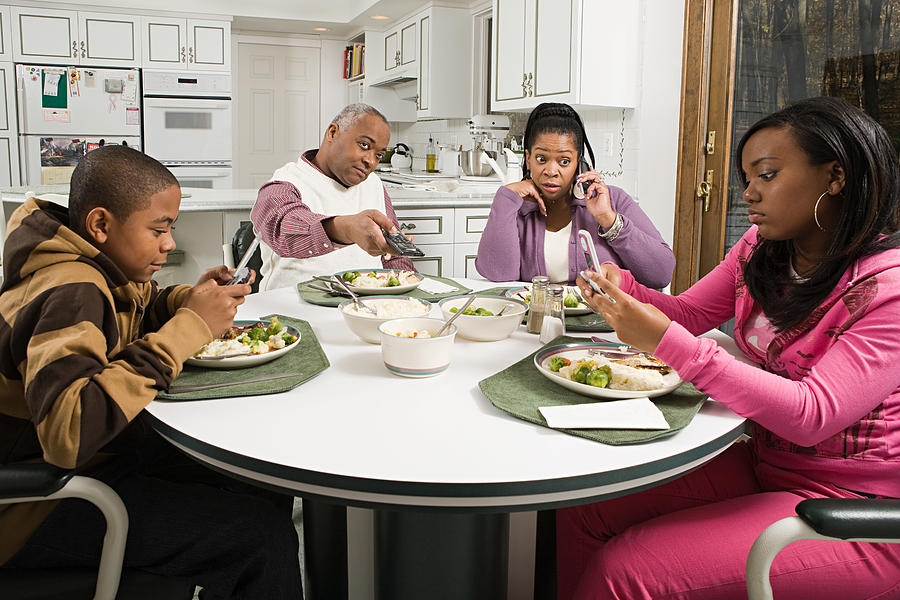 Distracted family at the dinner table Photograph by Image Source