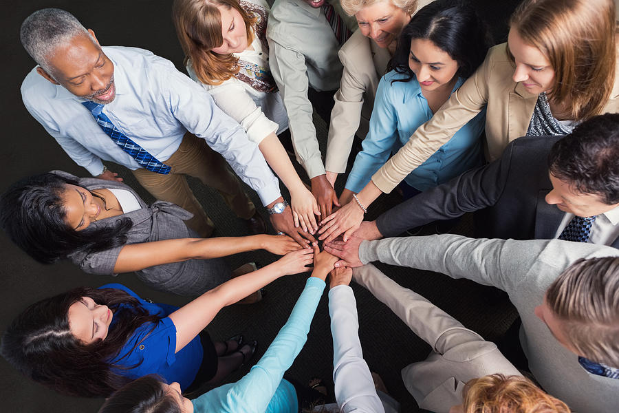 Diverse business team with hands in huddle to celebrate success Photograph by SDI Productions