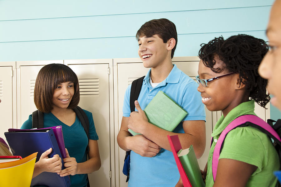 Diverse group of teenage students talk in school hallway. Lockers. Photograph by Fstop123