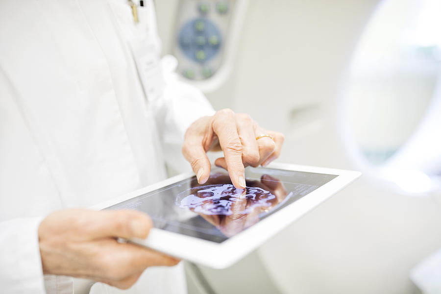 Doctor analyzing X-ray image in digital tablet Photograph by Alvarez