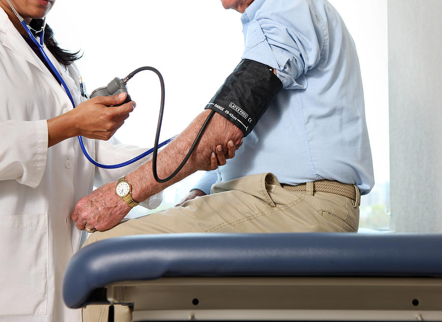 Doctor checks mans blood pressure. Photograph by Katrina Wittkamp