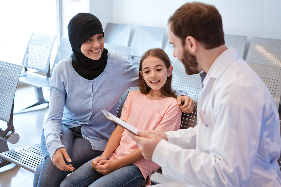 Doctor explaining to smiling girl and her mother Photograph by Izusek