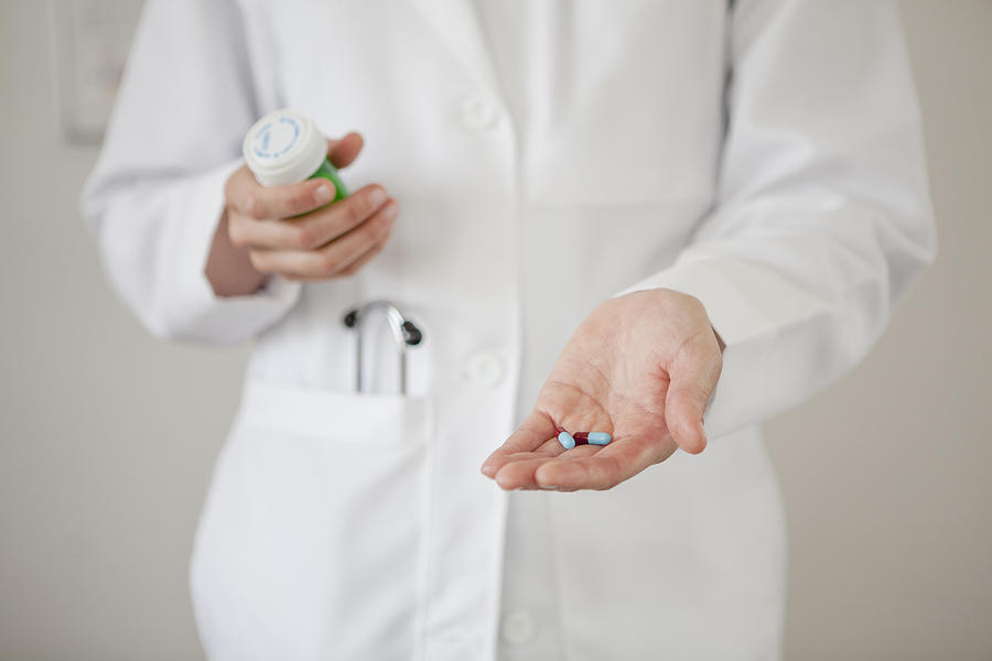 Doctor holding handful of pills Photograph by Blend Images - Hello Lovely