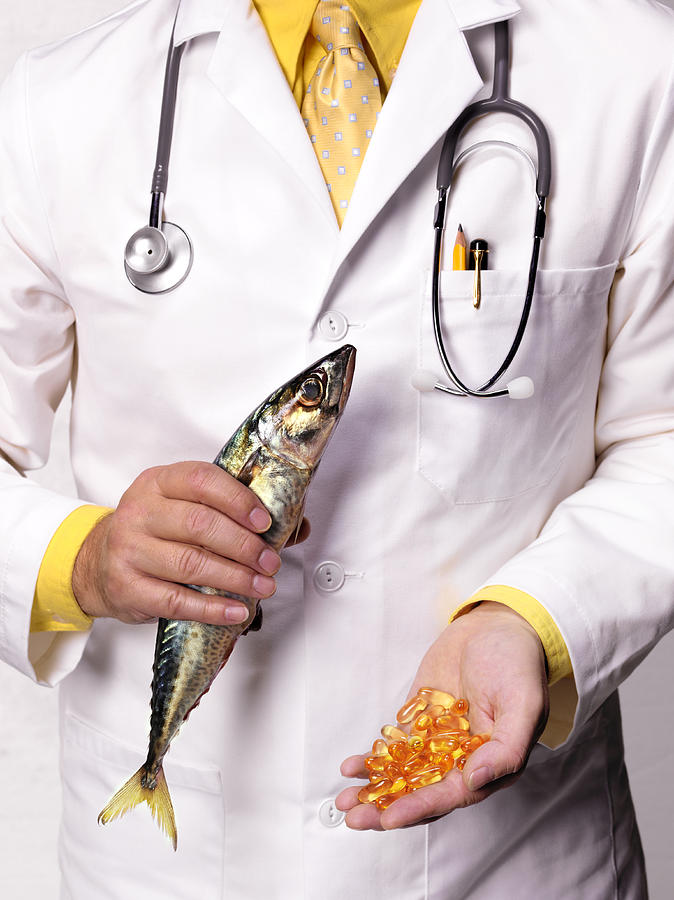 Doctor holding mackerel and Cod Liver oil tablets, close-up, mid section Photograph by Peter Dazeley