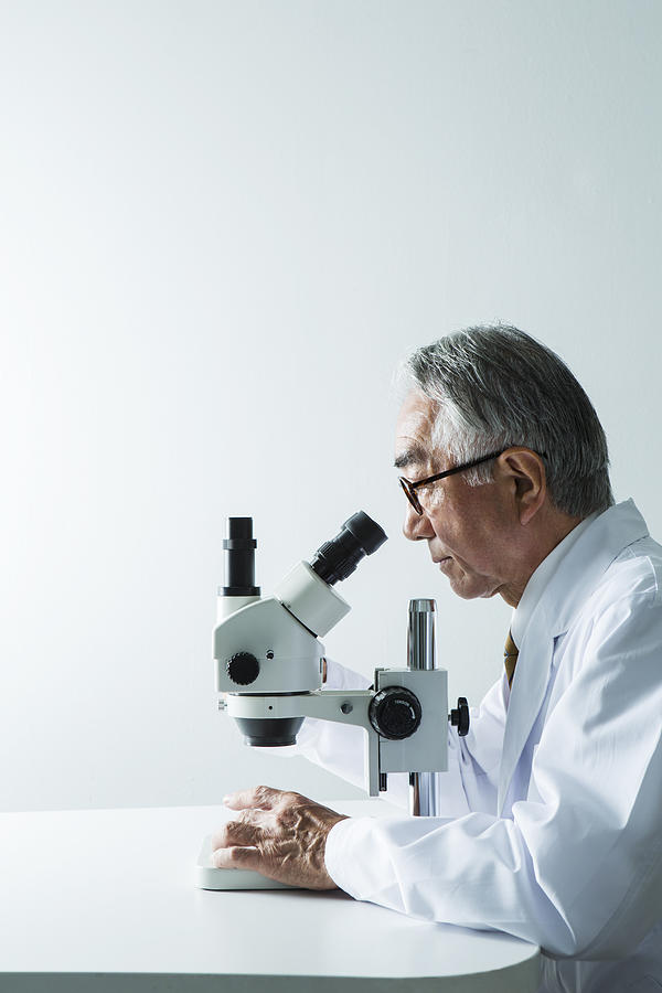Doctor looking through object using microscope Photograph by Indeed