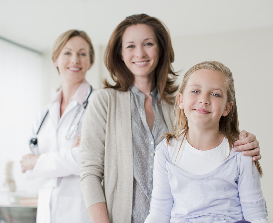 Doctor, mother and daughter in doctors office Photograph by Martin Barraud