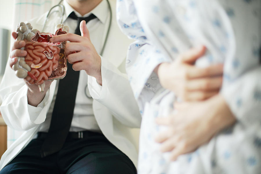 Doctor showing intestine model to patient in office Photograph by Runstudio