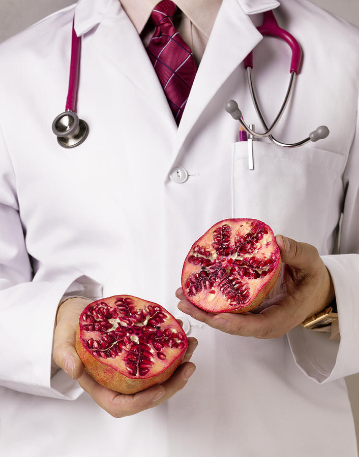 Doctor showing pomegranate, close-up, mid section Photograph by Peter Dazeley
