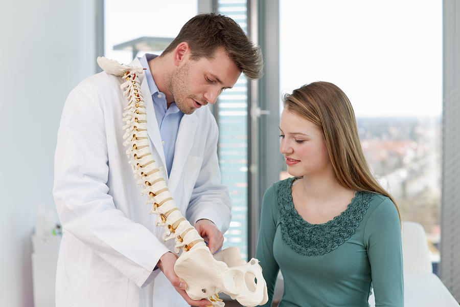 Doctor showing spine model to patient Photograph by Henglein and Steets