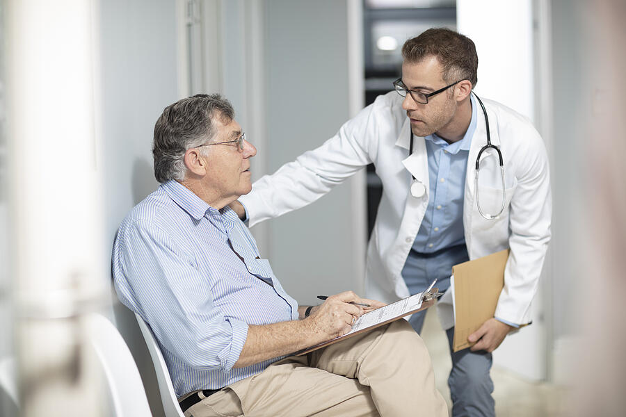 Doctor talking to patient with file in medical practice Photograph by Westend61