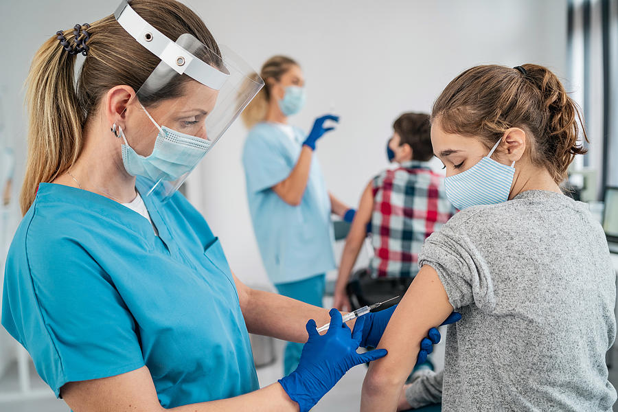 Doctor vaccinating girl. Injecting COVID-19 vaccine into patients arm Photograph by Valentinrussanov