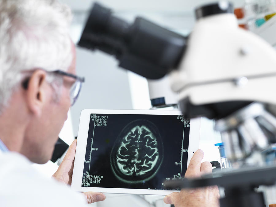 Doctor viewing a MRI brain scan on digital tablet in a laboratory Photograph by Andrew Brookes