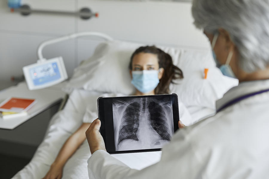 Doctor with digital x-ray by patient in ICU Photograph by Morsa Images