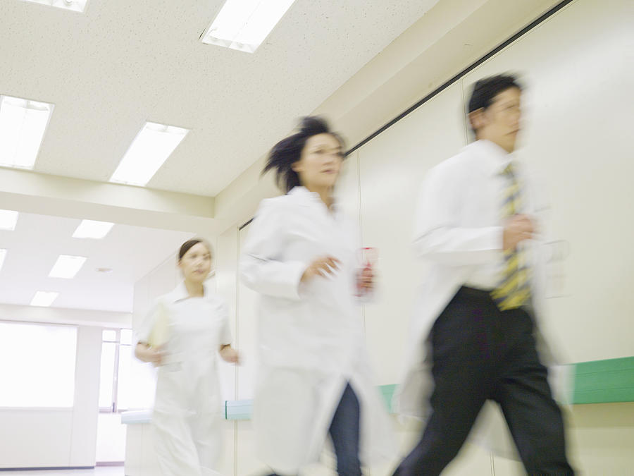 Doctors and nurse running in hospital corridor Photograph by Michael H