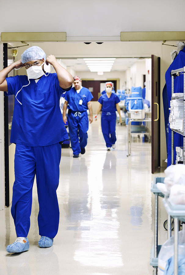 Doctors and nurses walking down hospital corridor. Photograph by Dana Neely