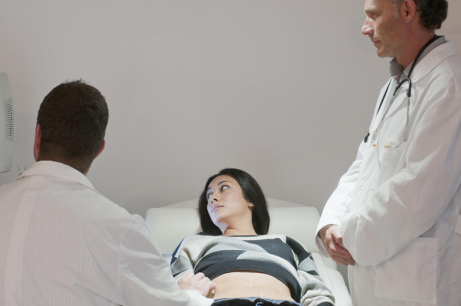 Doctors examining pregnant woman Photograph by Chris Sattlberger