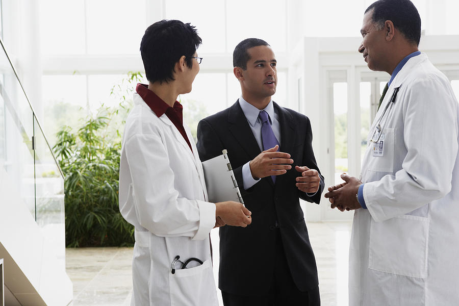 Doctors talking to businessman Photograph by Jon Feingersh Photography Inc