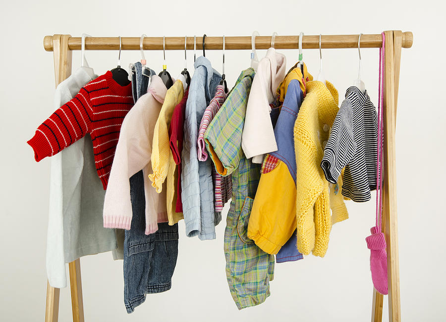 Dressing closet with baby clothes arranged on hangers. Photograph by Iulianvalentin
