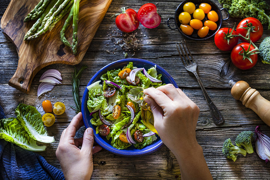 Dressing fresh organic vegetables salad with olive oil Photograph by Fcafotodigital