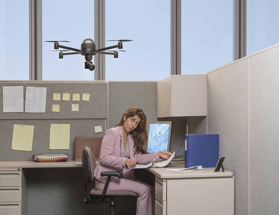 Drone hovering over Hispanic businesswoman in office Photograph by John M Lund Photography Inc