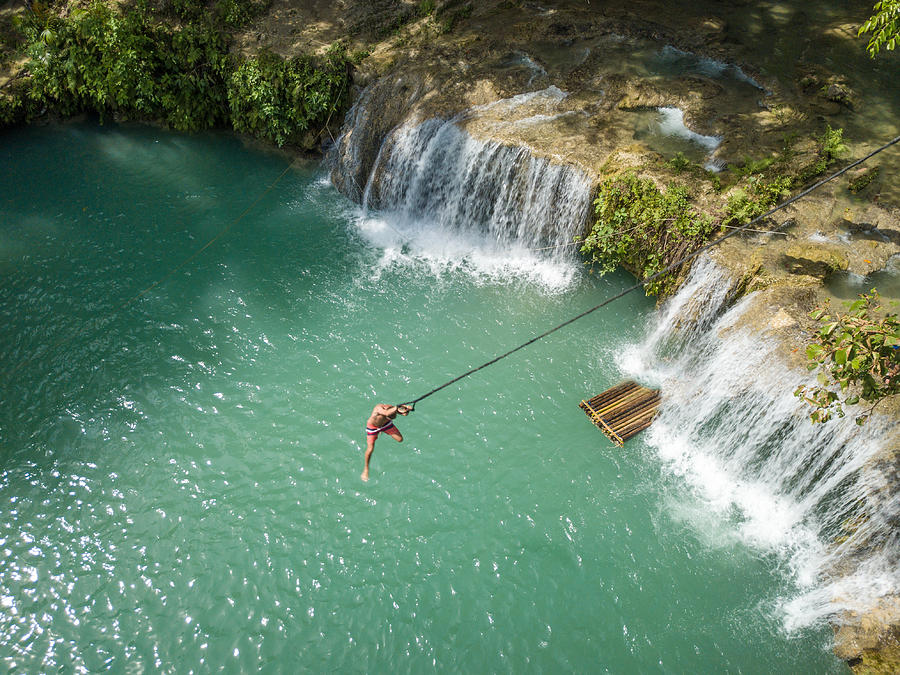 Drone point of view of man jumping into waterfall pool Photograph by Swissmediavision