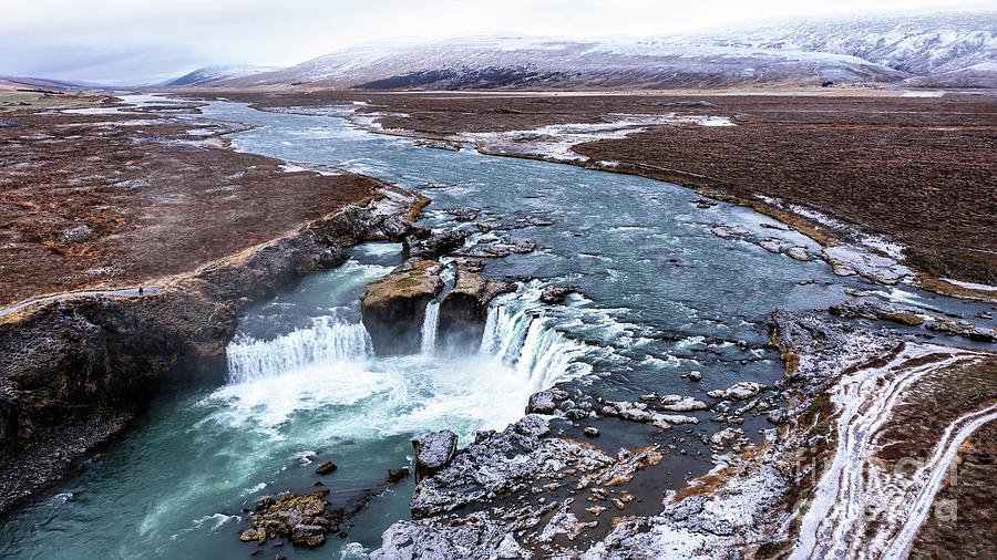 Drone shot of Godafoss waterfall, Iceland, taken from a high angle. Aerial view of the powerful cascade, river and snow covered rocks. Photograph by Jane Rix