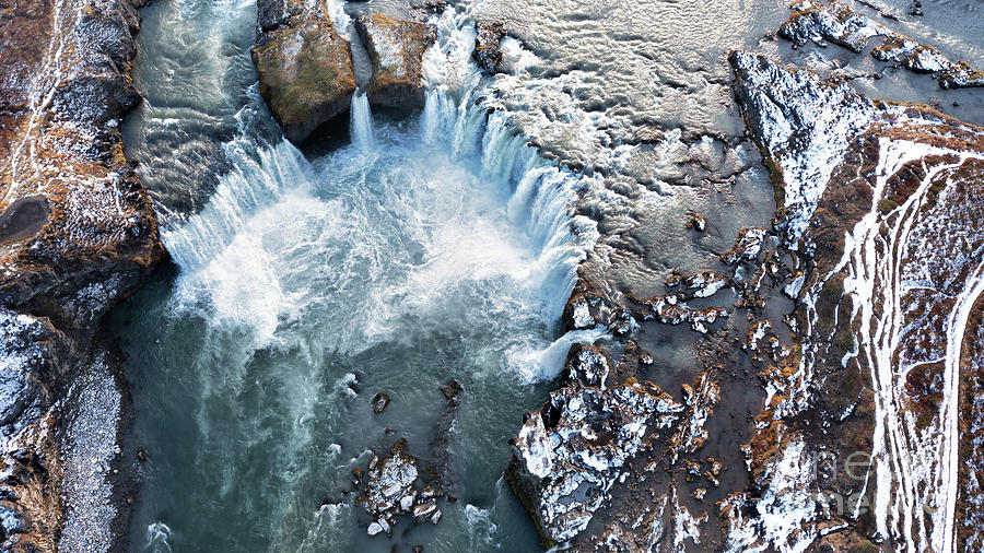 Drone shot of Godafoss waterfall, Iceland, taken from directly above. Aerial view of the powerful cascade, river and snow covered rocks. Photograph by Jane Rix