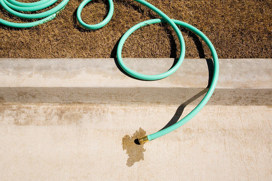 Dry lawn and garden hose on kerb Photograph by George Diebold