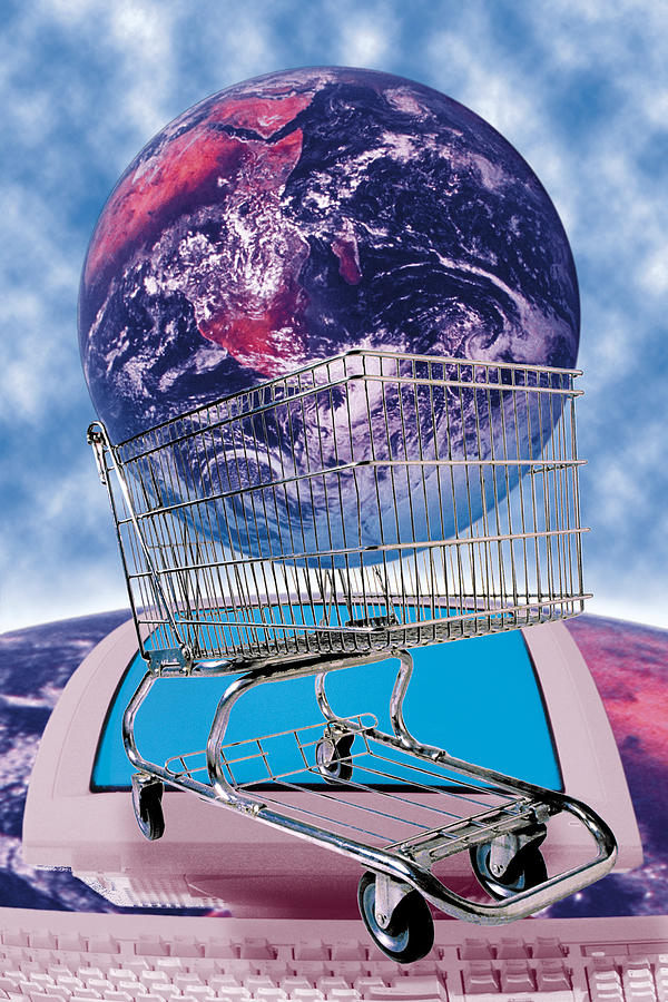 Earth in shopping cart on top of image of computer on Earth Photograph by Comstock