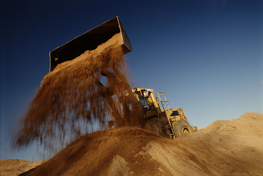 Earth mover in quarry dumping sand, low angle view Photograph by Justin Pumfrey
