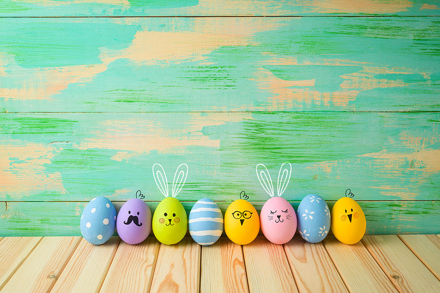 Easter eggs decorations on wooden table over colorful background Photograph by Maglara