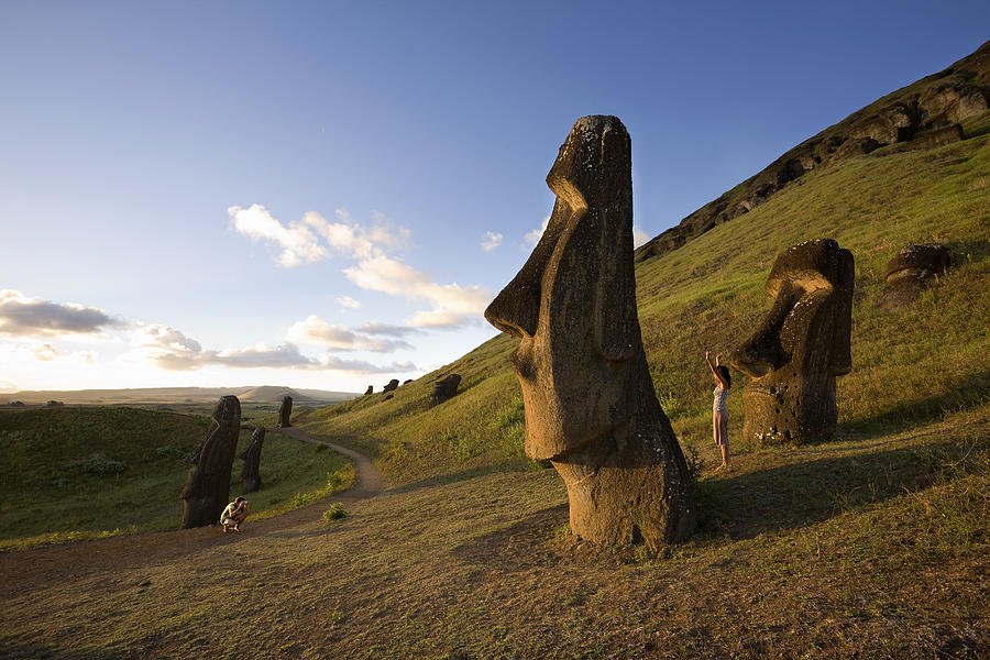 Easter Island, Rano Raraka, man photographing woman by ancient Moai statues Photograph by Michael Dunning