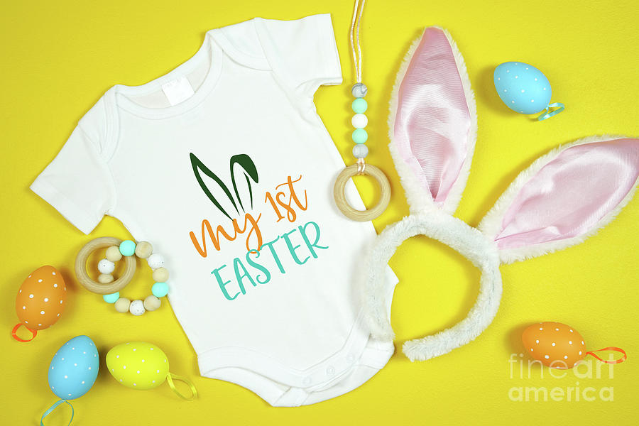 Easter Springtime baby apparel flatlay top view on yellow table. Photograph by Milleflore Images