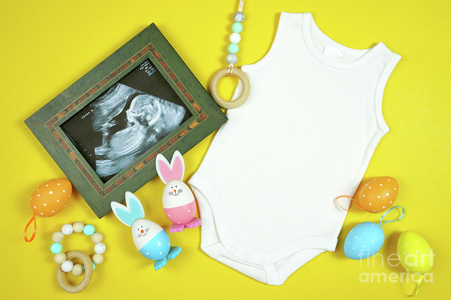 Easter Springtime baby apparel flatlay top view on yellow table. Mock up. Photograph by Milleflore Images