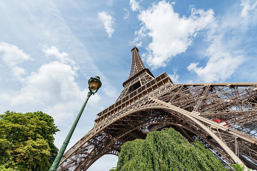 Eiffel tower and lamppost against blue sky in Paris Photograph by Philippe Lejeanvre