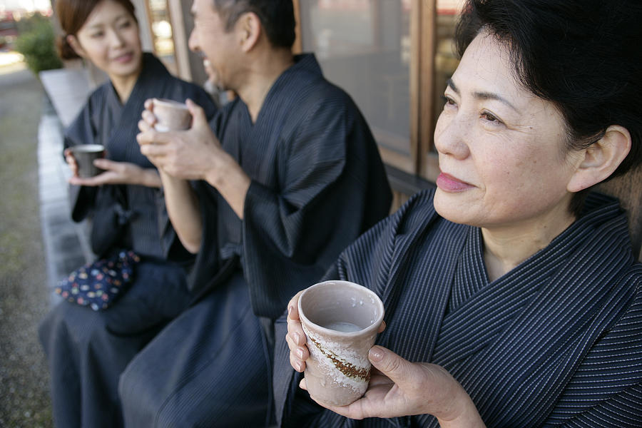 Elderly couple and young woman relaxing outdoor, holding cups Photograph by Traveling Spa