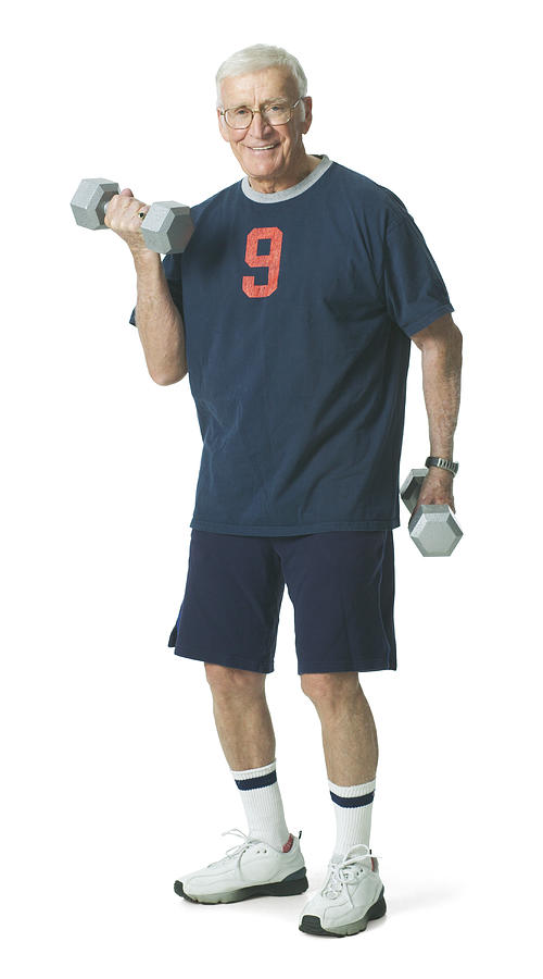 Elderly man smiles as he lifts weights. Photograph by Photodisc
