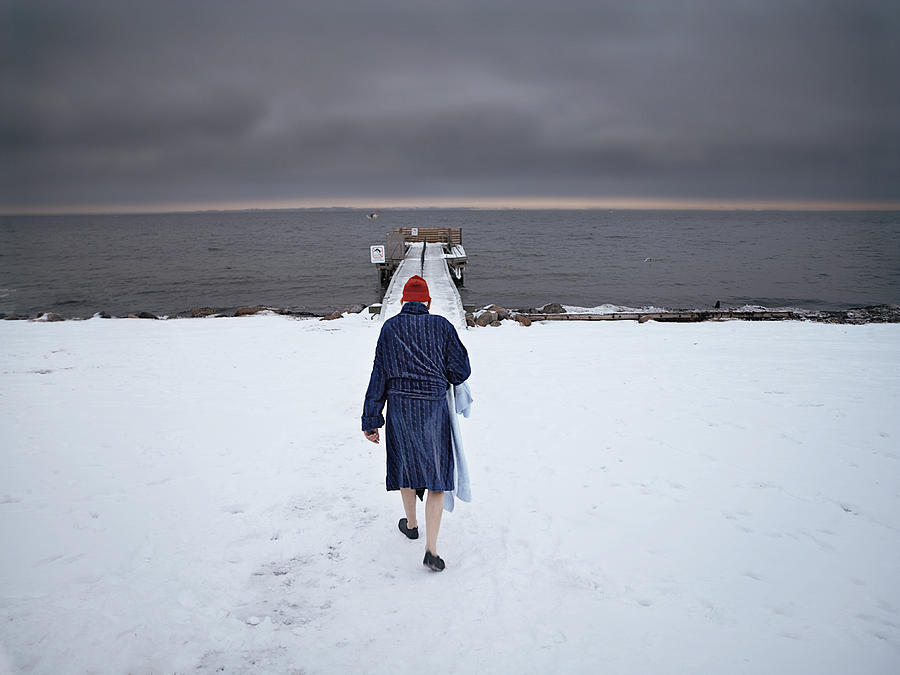 Elderly man walking towards to sea in the snow Photograph by David Trood