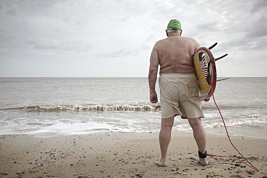 Elderly overweight surfer with back to camera Photograph by Jamie Garbutt