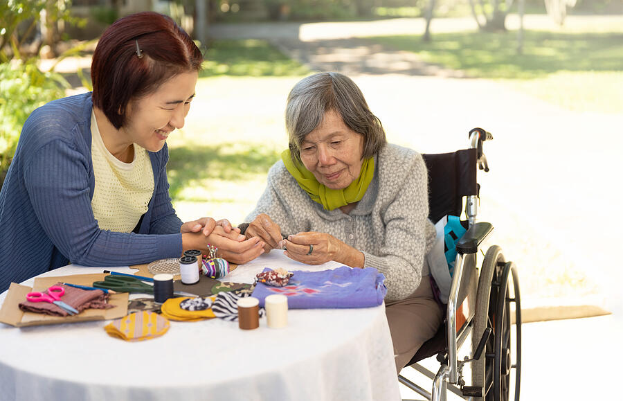 Elderly woman and daughter in the needle crafts occupational therapy for Alzheimer’s or dementia Photograph by Toa55