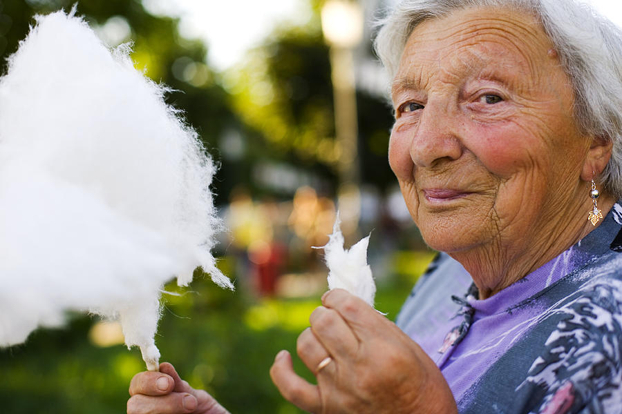 Elderly woman eating cotton candy at a fair Photograph by Rollover