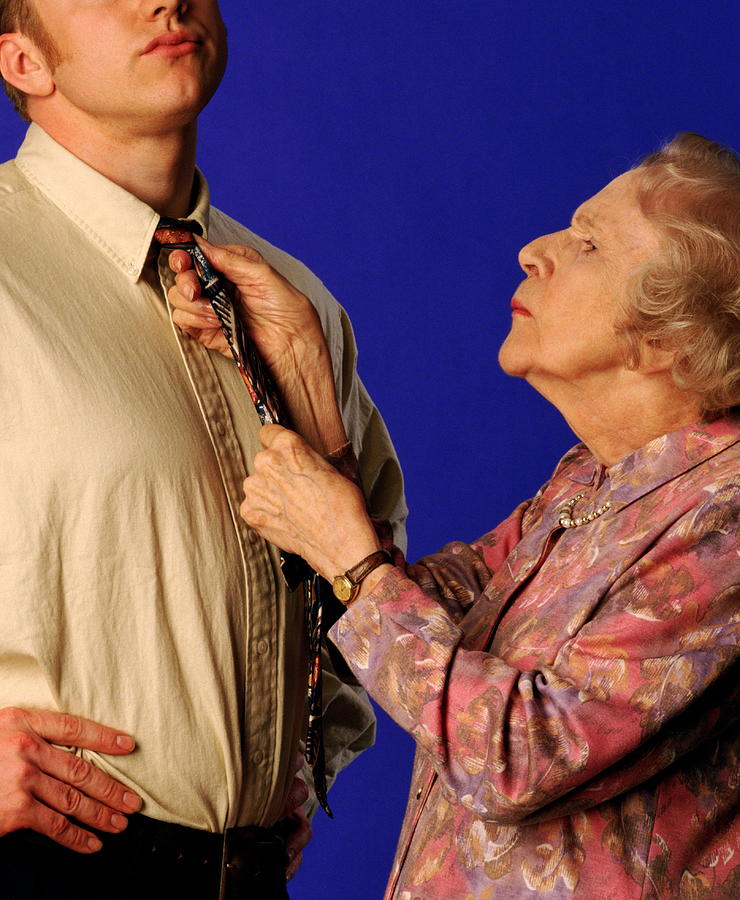 Elderly woman tying young mans tie, close-up Photograph by Robert Daly