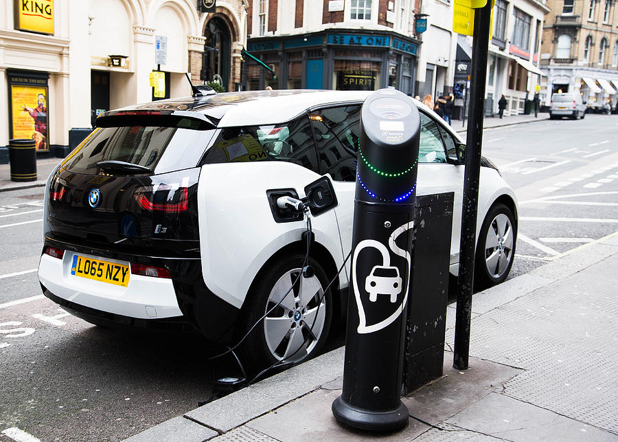 Electric car being recharged at a meter in London, UK Photograph by SashaFoxWalters