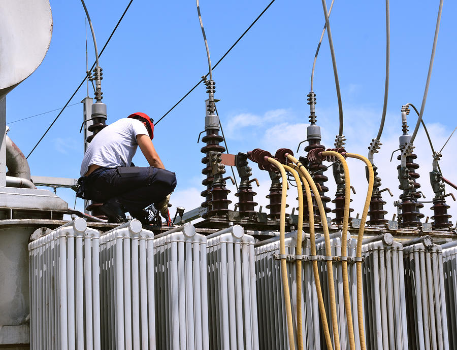 Electrician working on high voltage transformer in power station Photograph by Shinyfamily