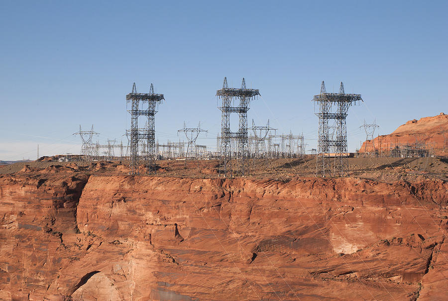 Electricity pylons over a dam Photograph by Fotosearch