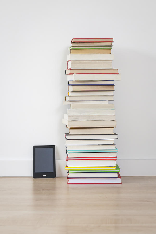 Electronic book reader next to stack of books Photograph by Steven Errico