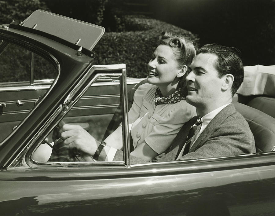Elegant couple riding in in convertible car, (B&W) Photograph by George Marks