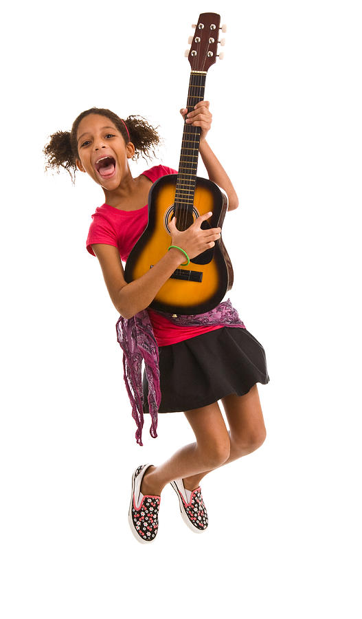 Elementary age female jumping in air and playing guitar Photograph by LattaPictures
