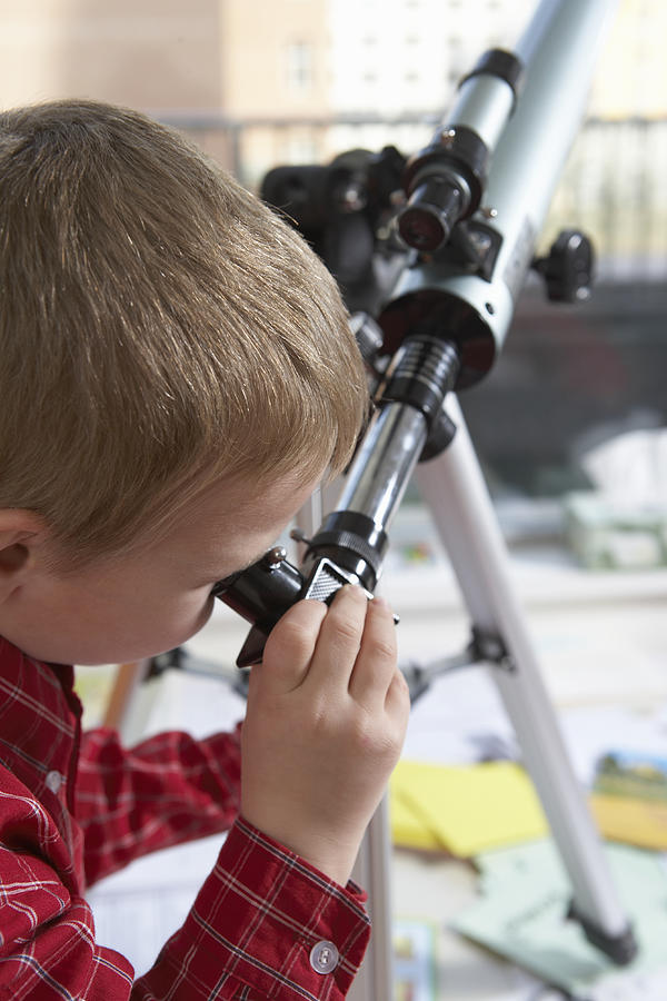 Elementary school boy uses a telescope Photograph by Blue Jean Images